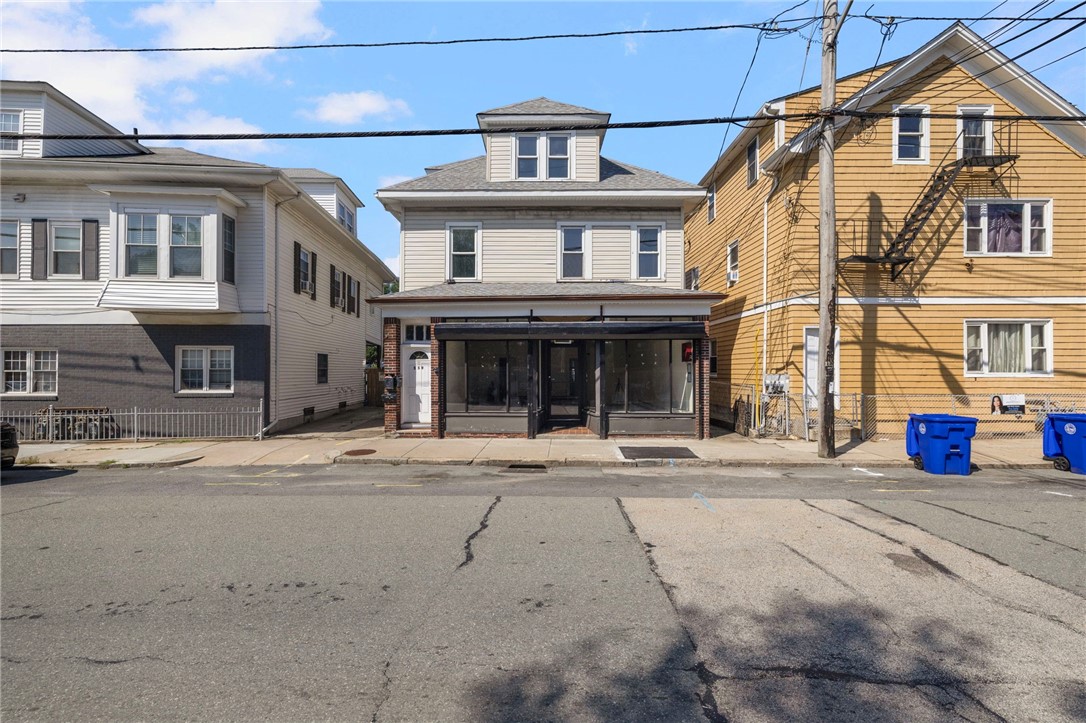 Two-story beige building with a glass-fronted storefront on an urban street.