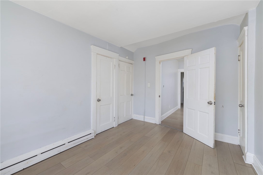 Empty room with light wood plank flooring and several white paneled doors.