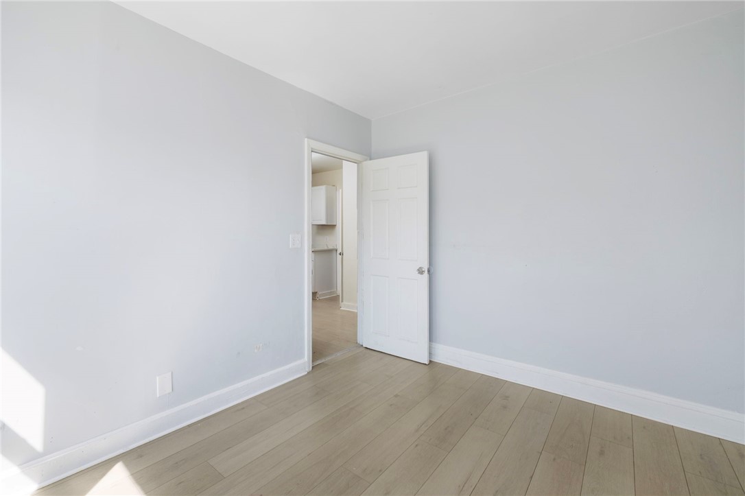 Empty room with gray walls, light plank flooring, and an open door.