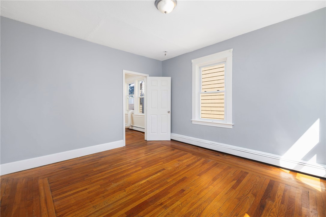 Empty room with pale blue-gray walls, white trim, and polished hardwood floors.