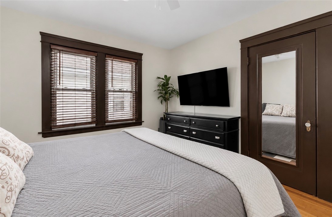 Bedroom with a gray quilted bed, dark wood trim, and a mirrored closet door.