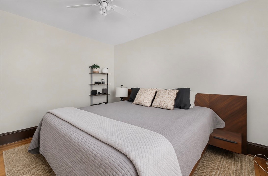 Bedroom with gray quilted bedding, patterned pillows, and a dark wood headboard.