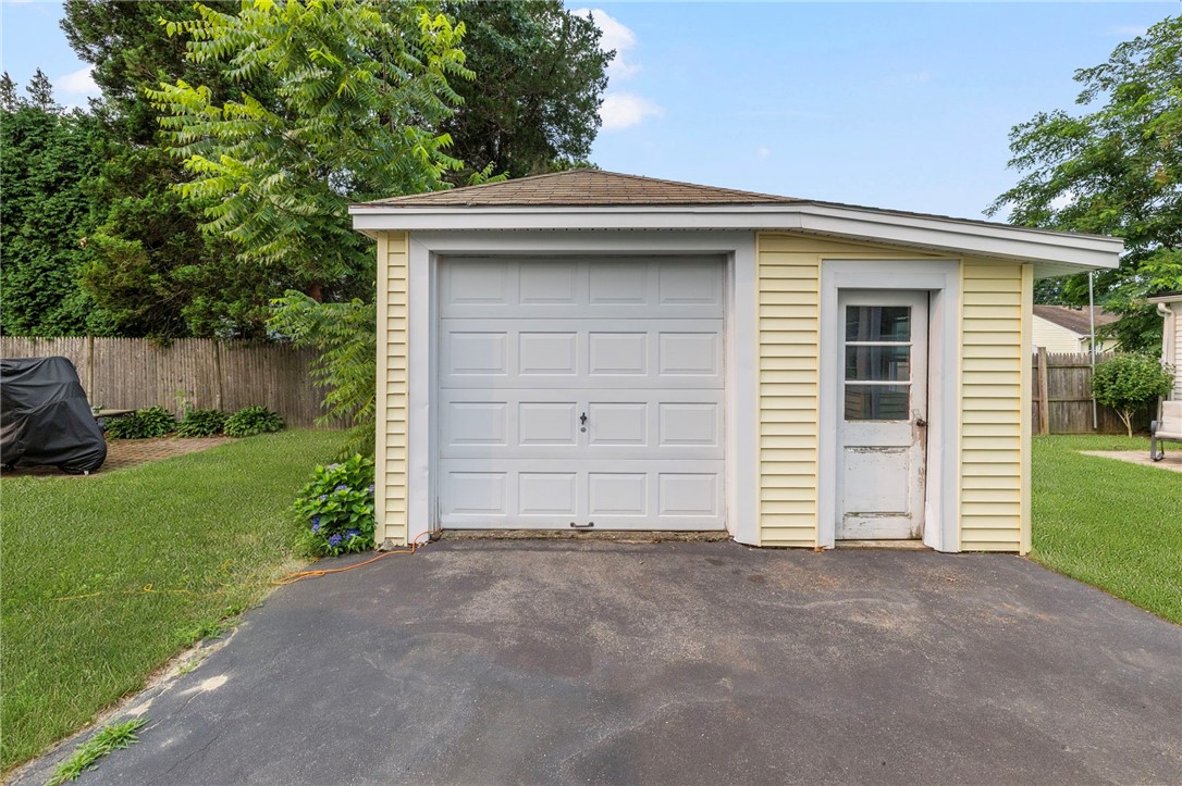 Detached pale-yellow garage with a white overhead door and separate side entrance.