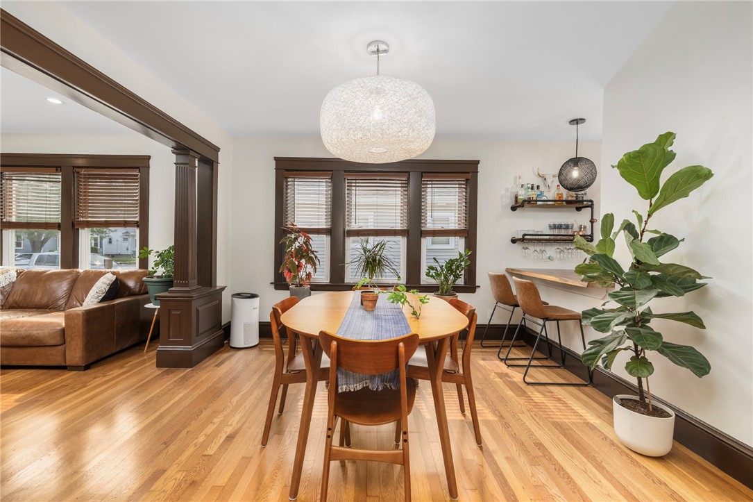 Dining room with a round wooden table, hardwood floors, dark trim, and an adjoining living room.