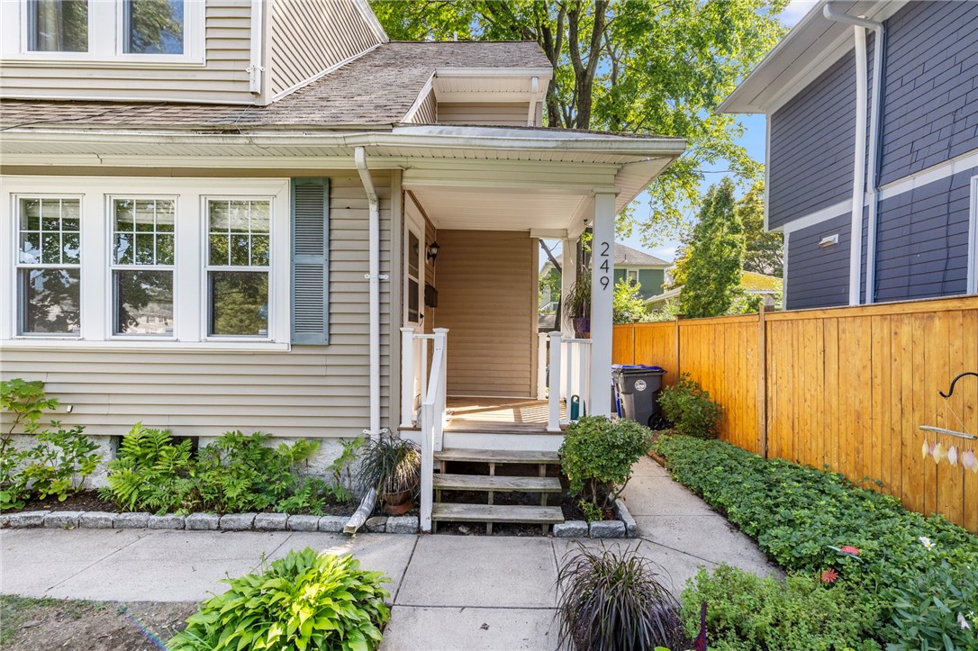 Home exterior with a covered porch, front steps, and a landscaped walkway beside a wooden fence.