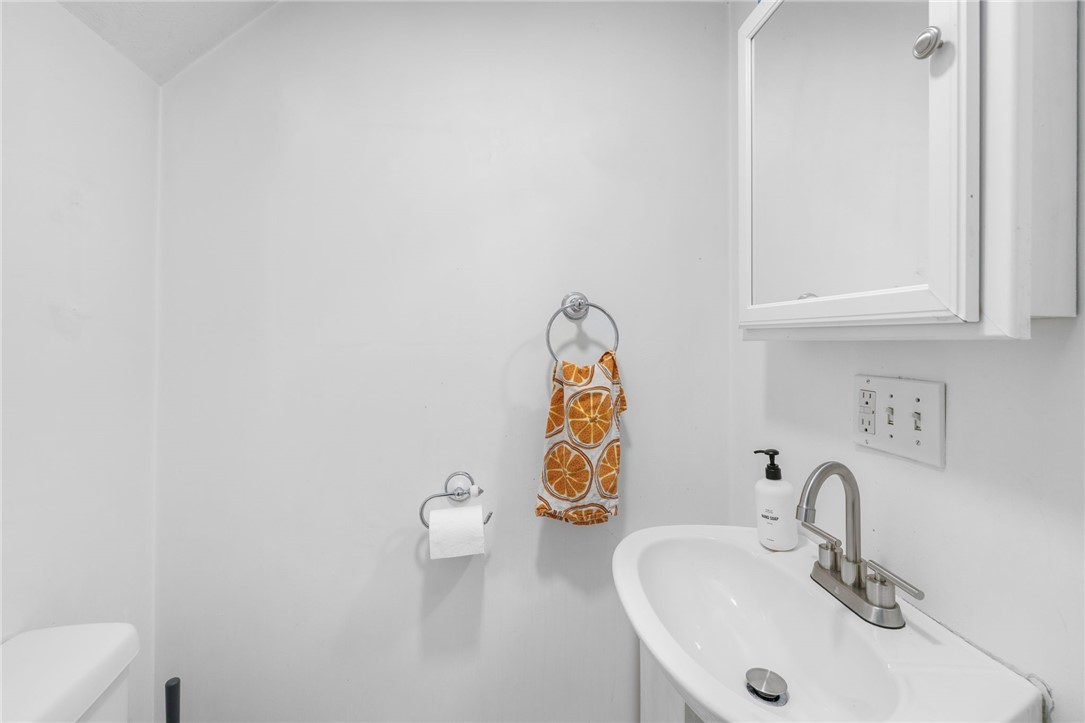 Bathroom sink beneath a mirrored medicine cabinet, with an orange-patterned hand towel.