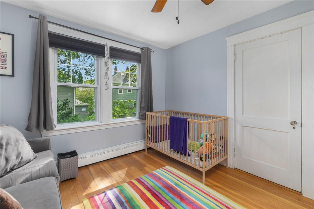 Nursery with a wooden crib beside large windows and a colorful striped rug.