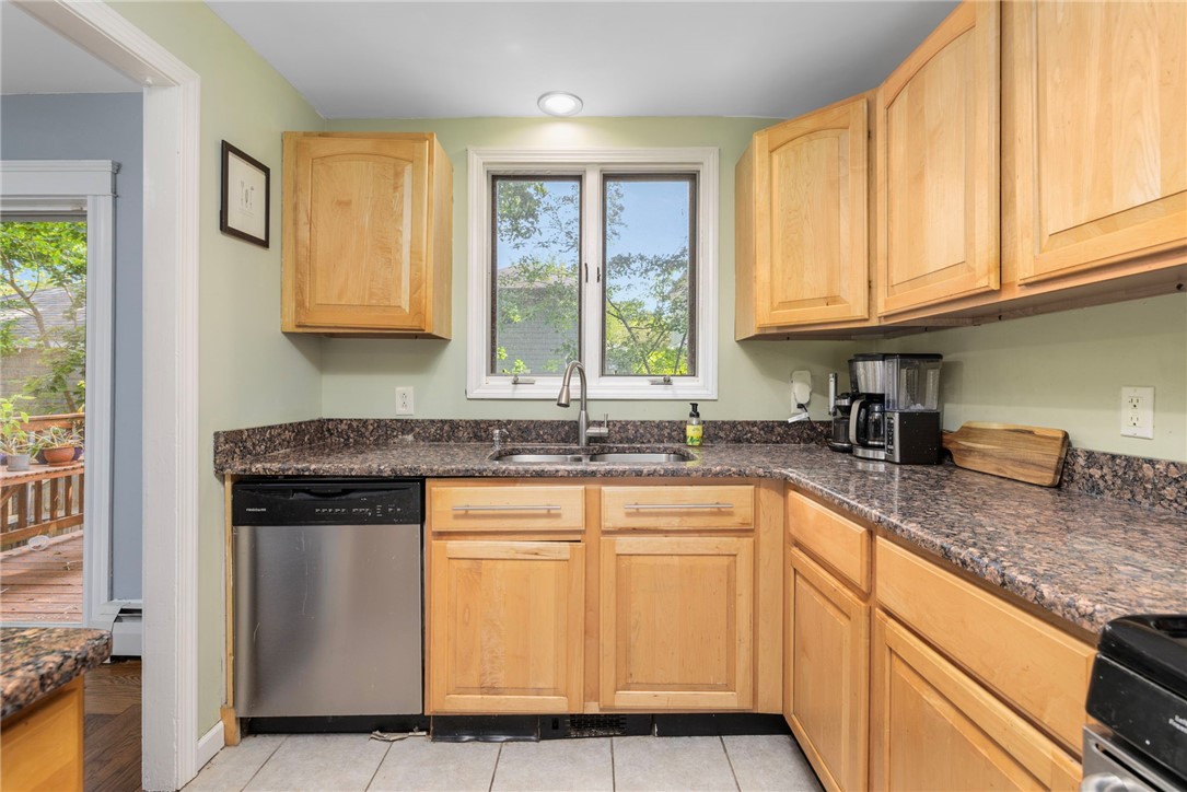 Kitchen with light wood cabinetry, granite counters, and a sink beneath a window.