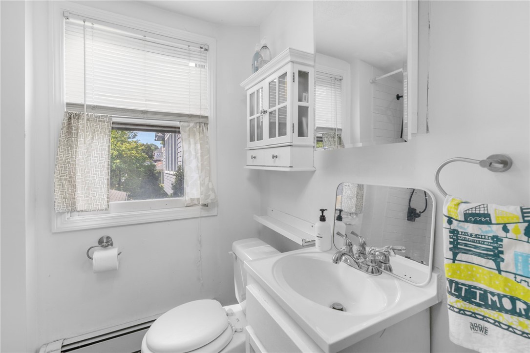 Bathroom with a white vanity, toilet, and window with patterned curtains.