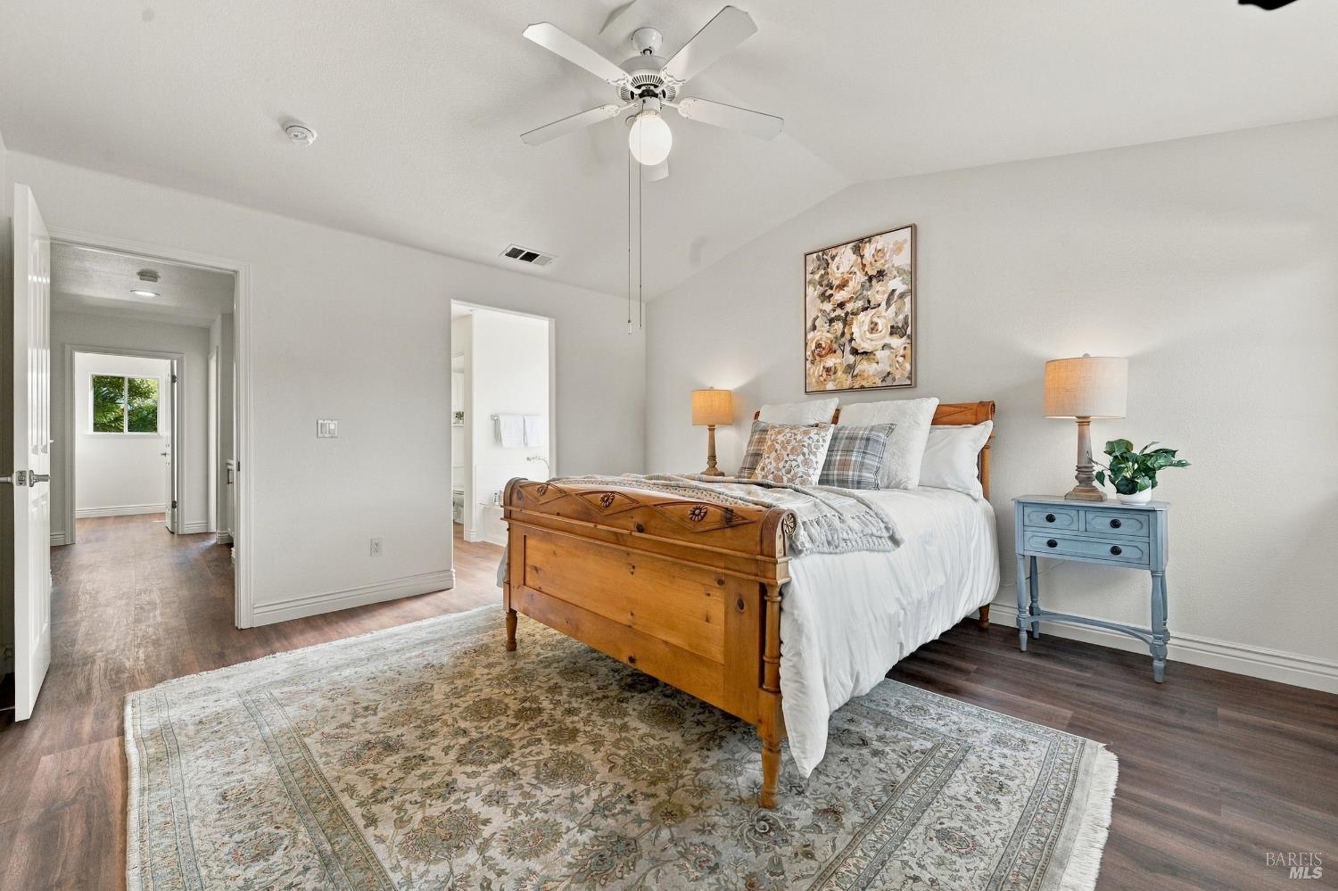 Furnished bedroom with a carved wooden bed, ceiling fan, and patterned area rug.