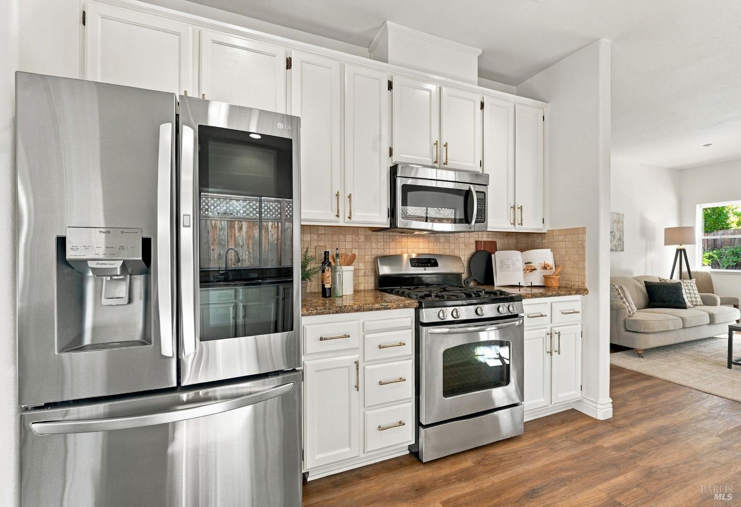 Kitchen with white shaker cabinets, stainless steel appliances, granite counters, and hardwood floors.