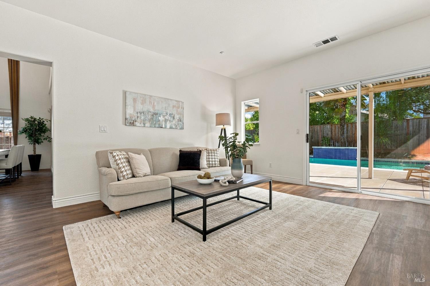 Living room with a beige sofa and sliding doors overlooking a backyard pool.