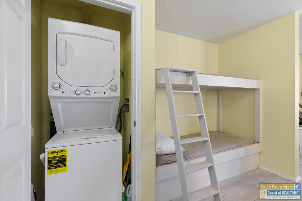 Bedroom with a built-in bunk bed beside an open closet containing a stacked washer and dryer.
