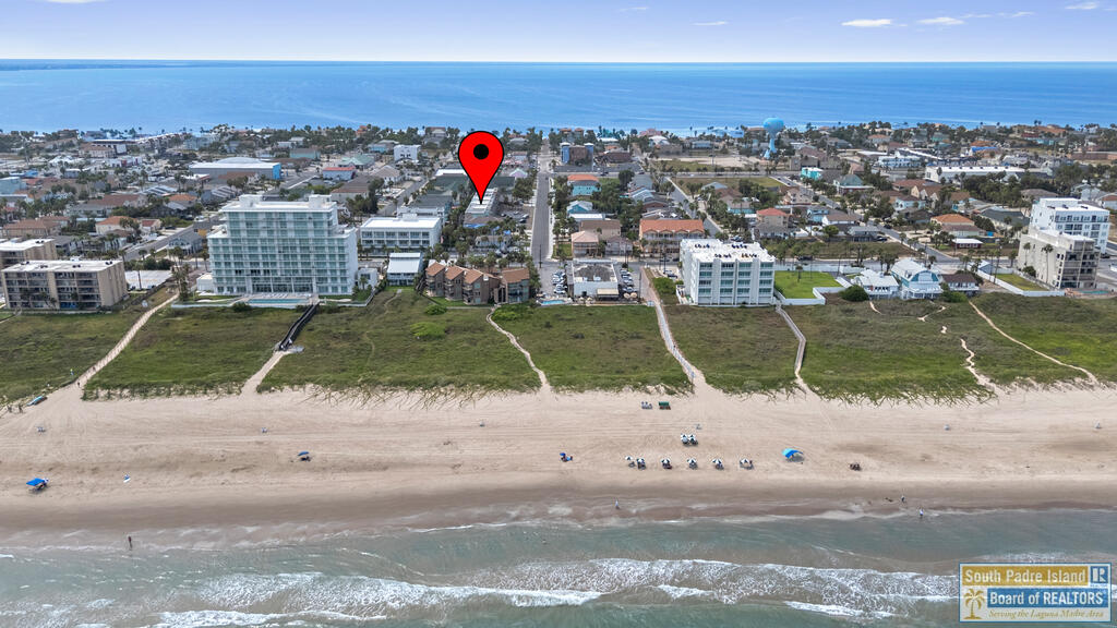 Aerial view of South Padre Island beachfront, with a red map pin over homes between the ocean and beach.