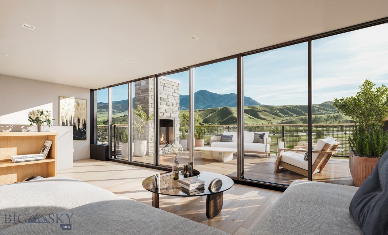 Living room with floor-to-ceiling windows, a stone fireplace, and mountain views.