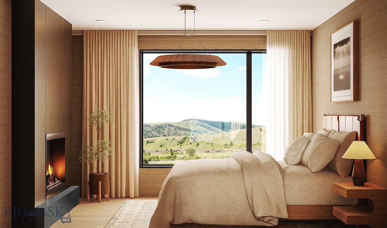 Bedroom with a built-in fireplace and a large window overlooking rolling green hills.