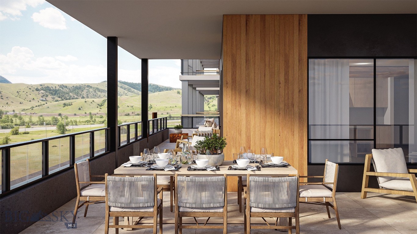 Covered terrace with a set dining table overlooking green hills and mountains.