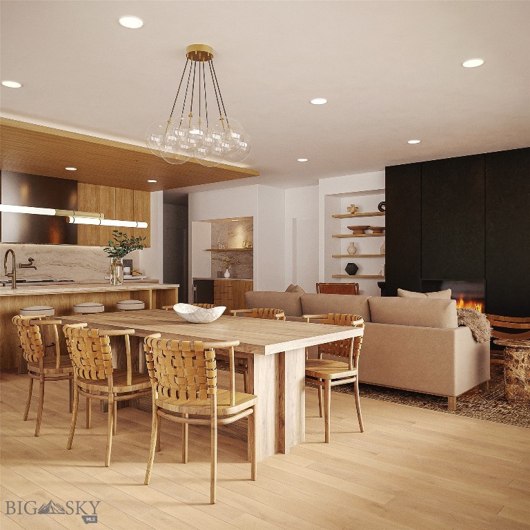 Open-plan dining and living area with a long wood table, woven chairs, and a dark fireplace wall.