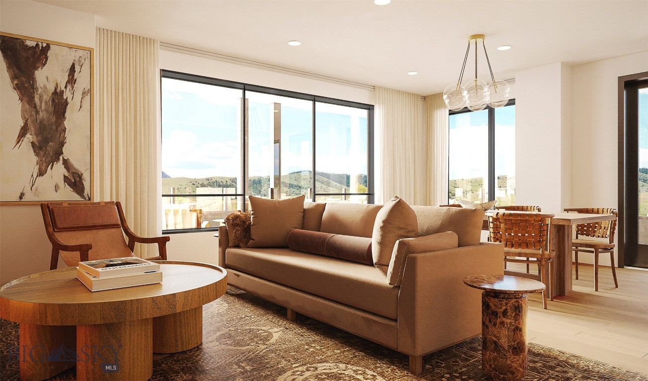 Living room with a tan sofa, floor-to-ceiling windows, and views of rolling hills.