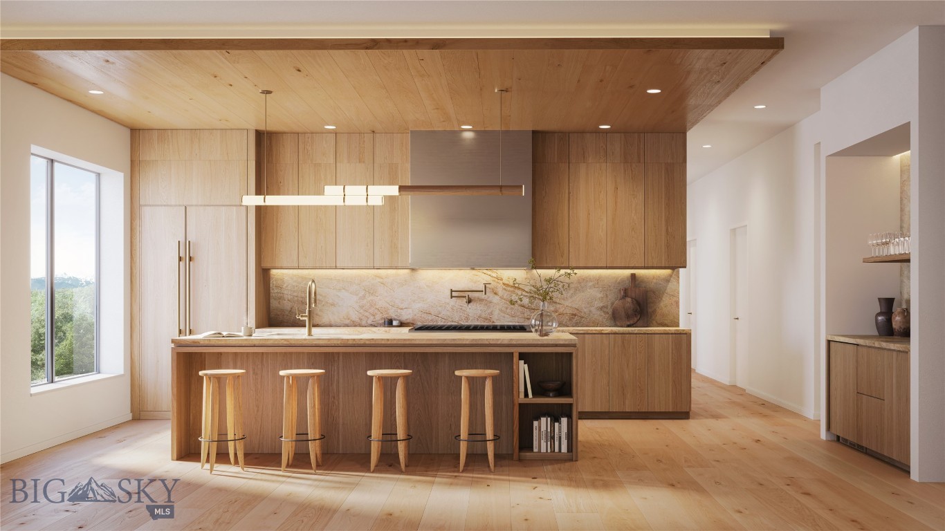 Modern wood kitchen with island seating, stone backsplash, and mountain views through a large window.