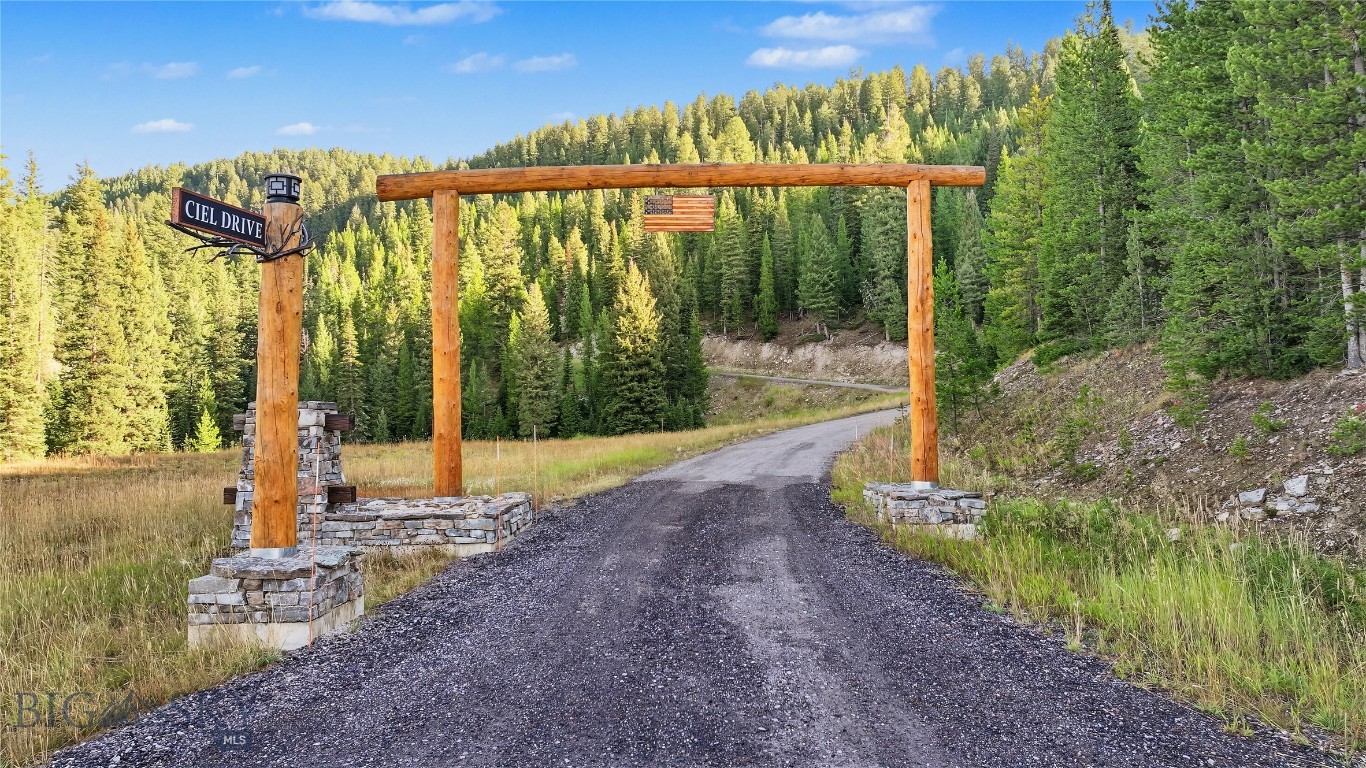 Ciel Drive entrance with a timber arch over a gravel road in a forested setting.