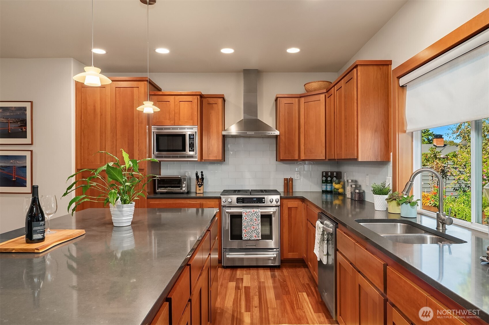 Kitchen with warm wood cabinets, gray counters, stainless steel appliances, and a large island.