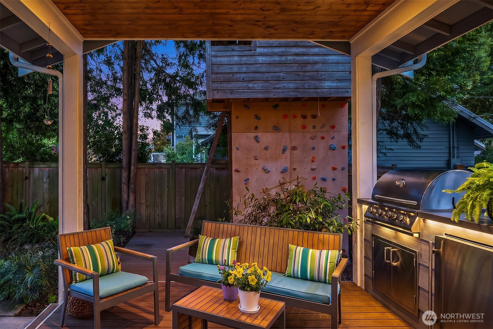 Covered patio with cushioned seating, a built-in barbecue, and a climbing wall.
