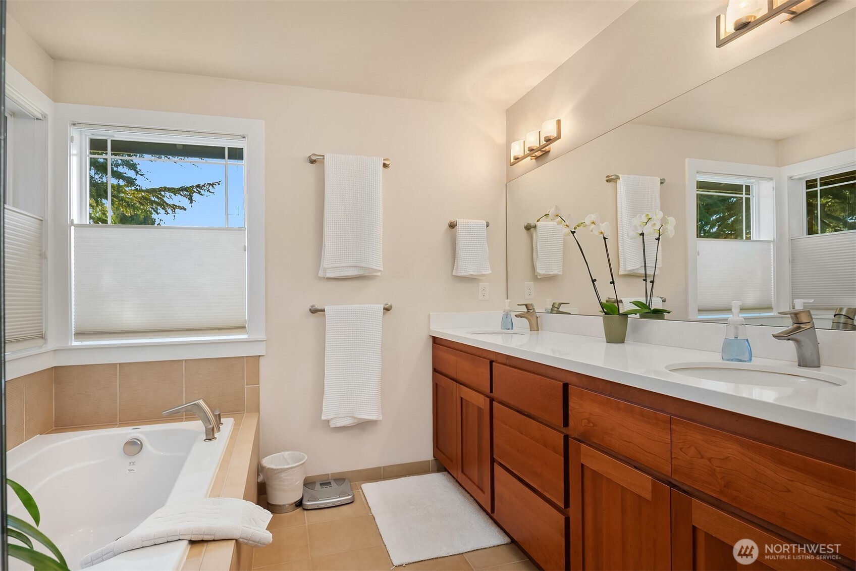 Bathroom with a soaking tub and double vanity with warm wood cabinets.