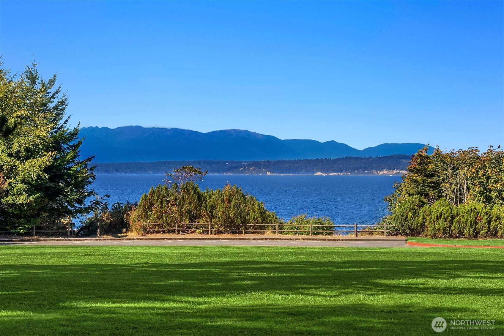 Waterfront view across a green lawn toward distant mountains.