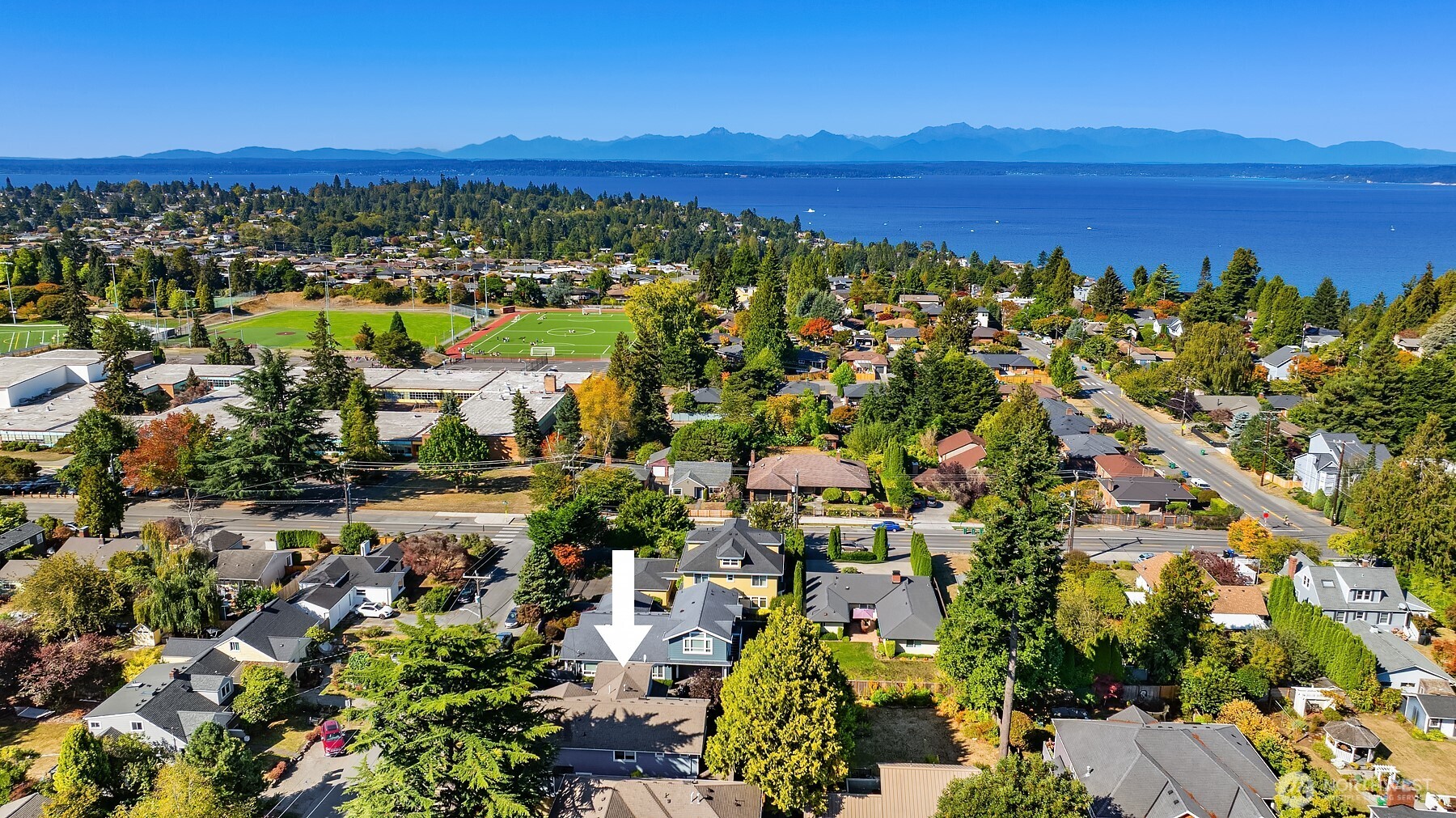 Aerial view of the marked Seattle home, with Puget Sound and distant mountains beyond the neighborhood.