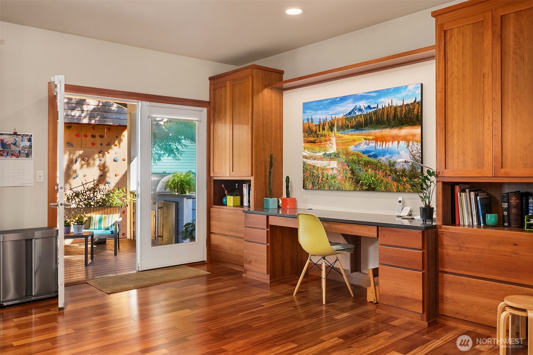 Home office with cherry built-ins and hardwood floors, opening onto a deck with a climbing wall.