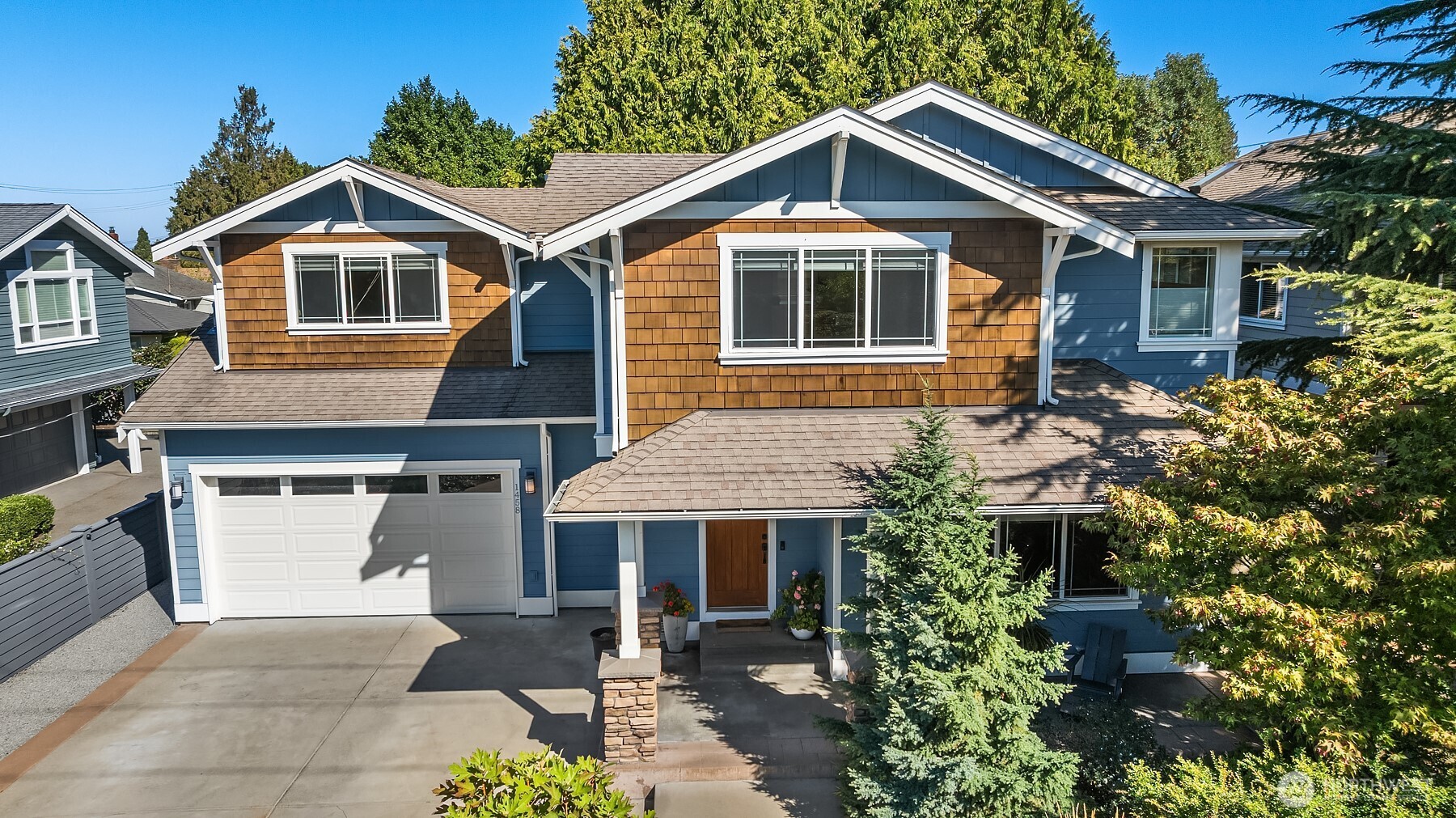 Blue two-story house with cedar-shingle gables, attached garage, and landscaped entry.
