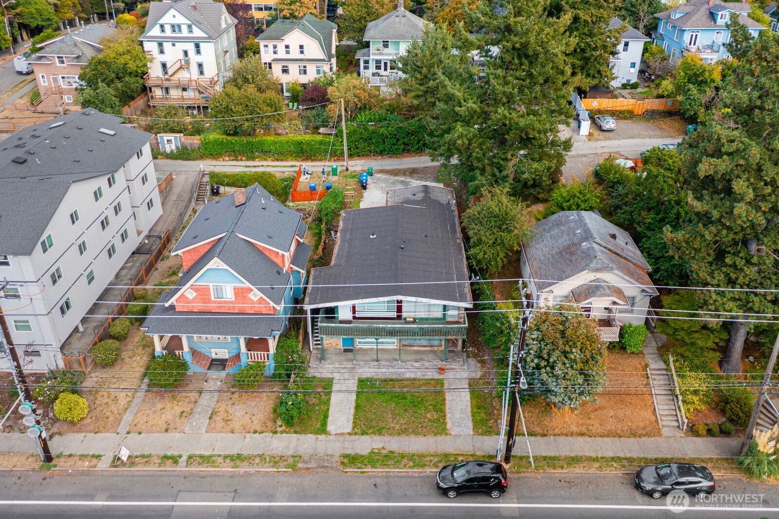 Aerial view of a green two-story house among neighboring homes and autumn trees.