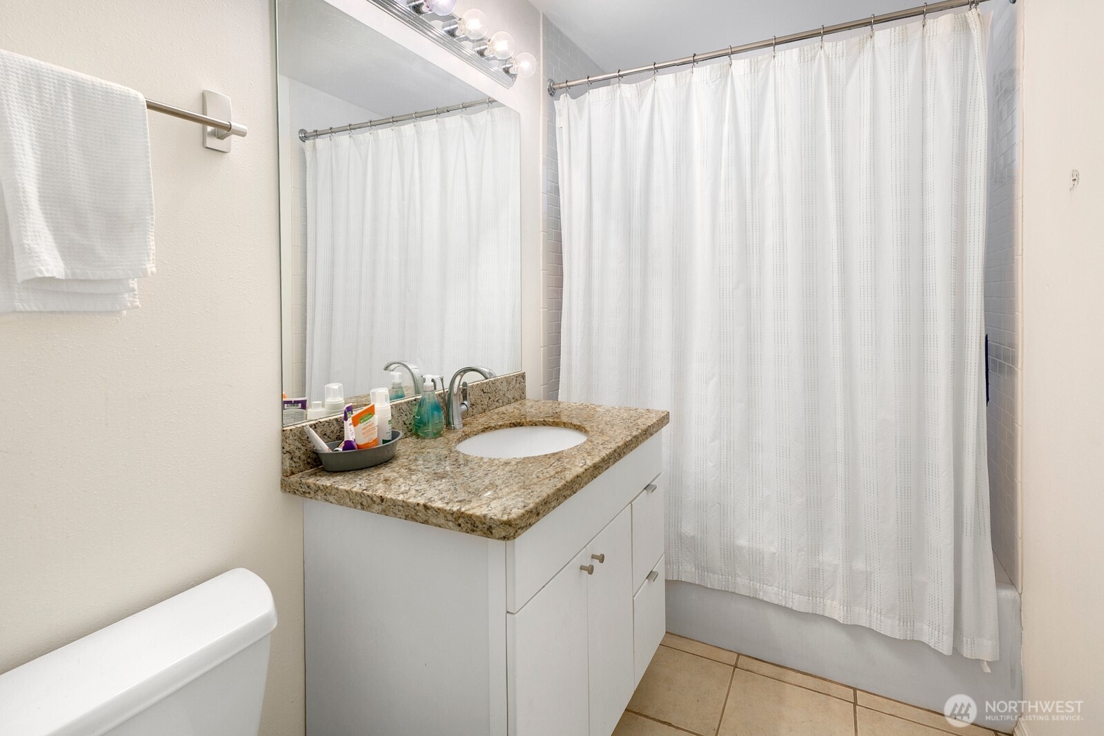 Bathroom with a granite vanity, large mirror, and white shower curtain.