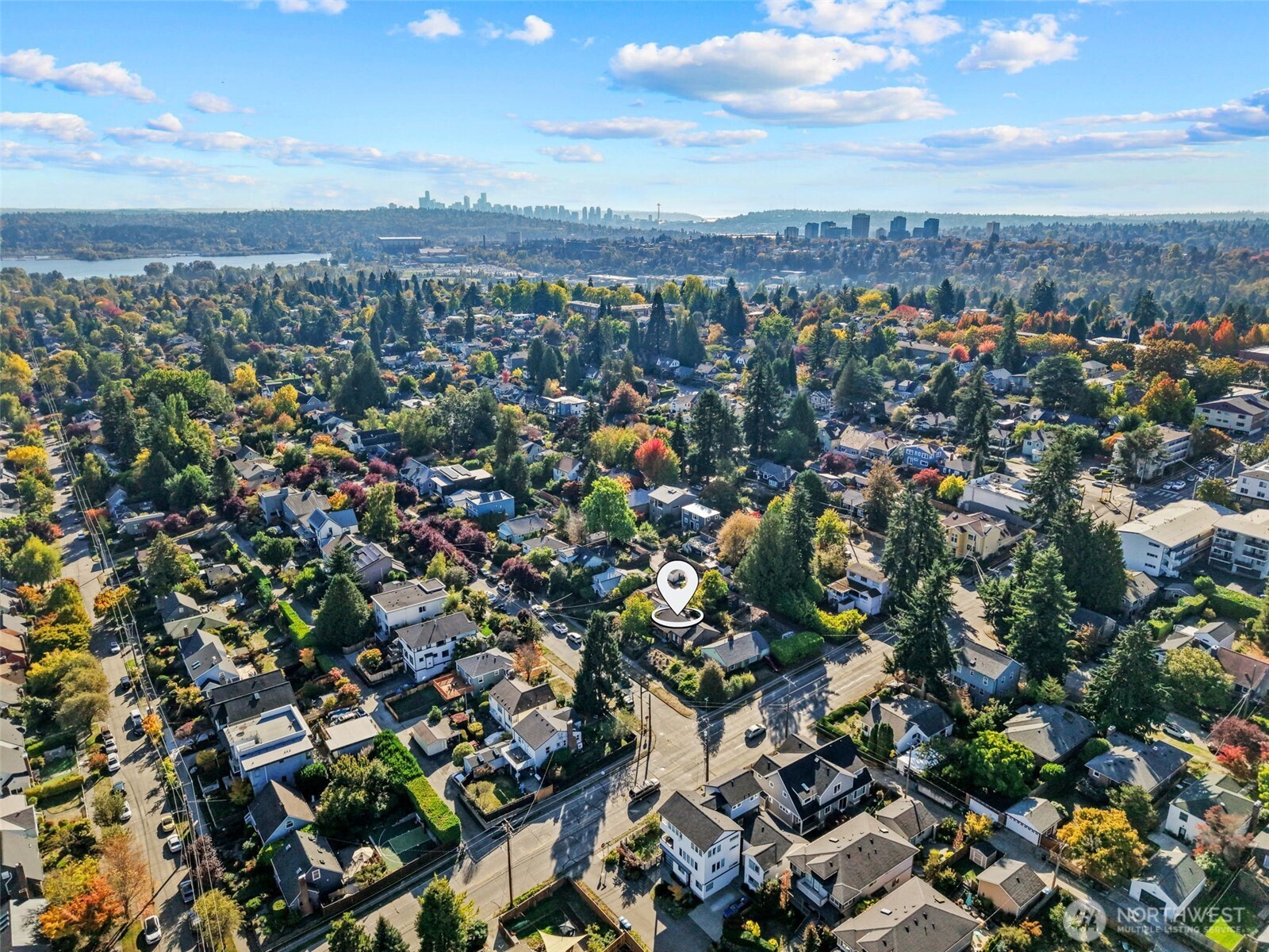 Aerial view of the property and leafy Seattle neighborhood, with downtown skyline and water in the distance.