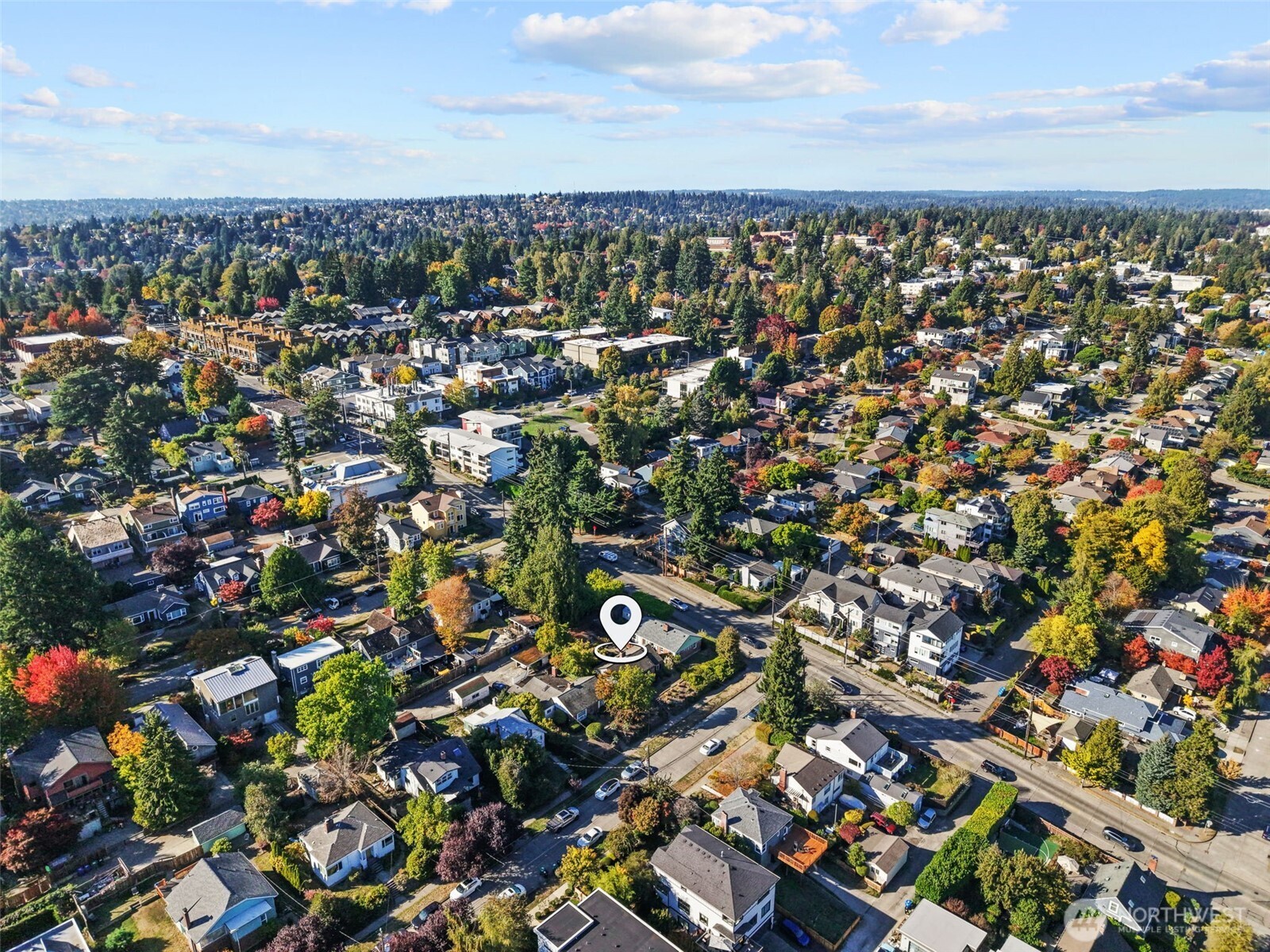 Aerial view of a Seattle neighborhood in autumn, with a map pin marking a home among tree-lined residential streets.