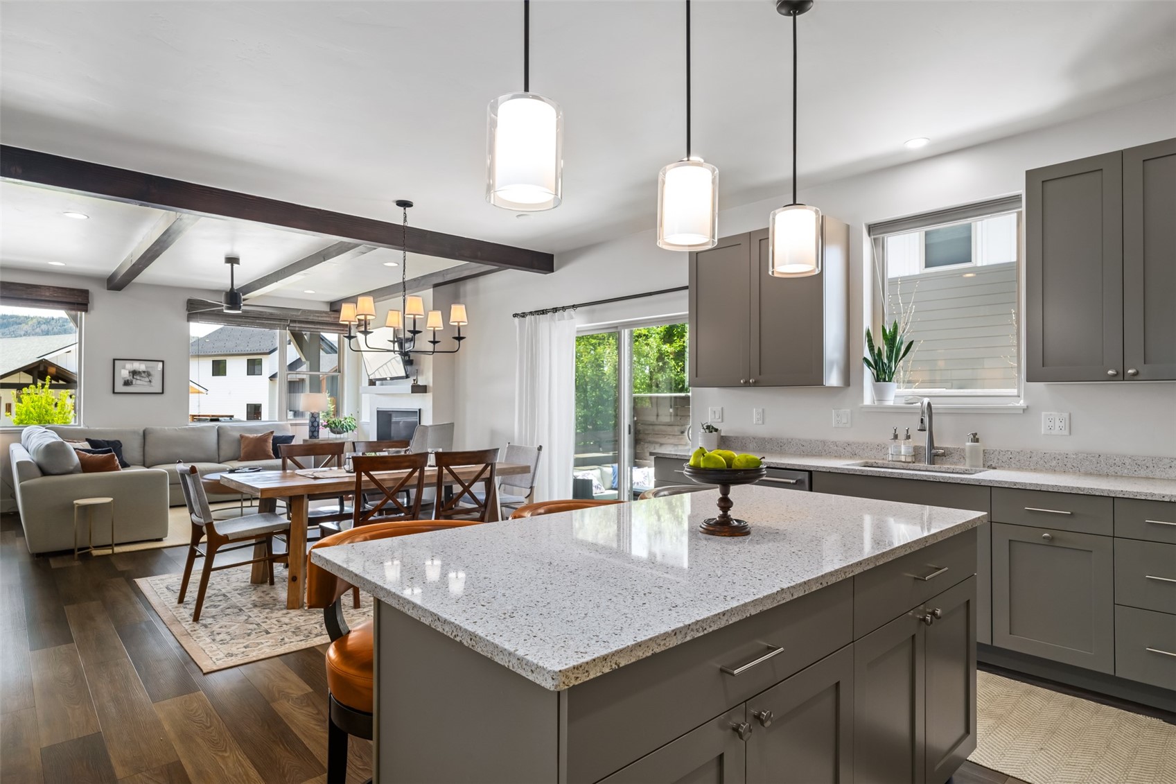 Open-plan kitchen and living room with a large stone island and exposed ceiling beams