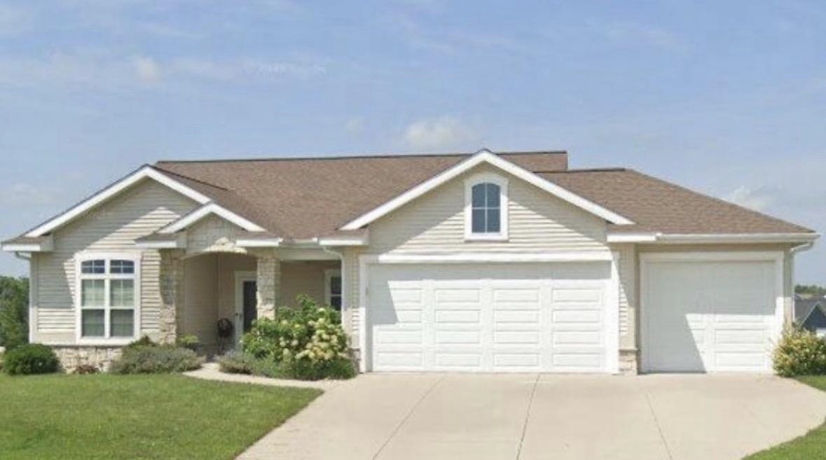 Single-story beige house with stone accents, a covered entry, and a three-car garage.