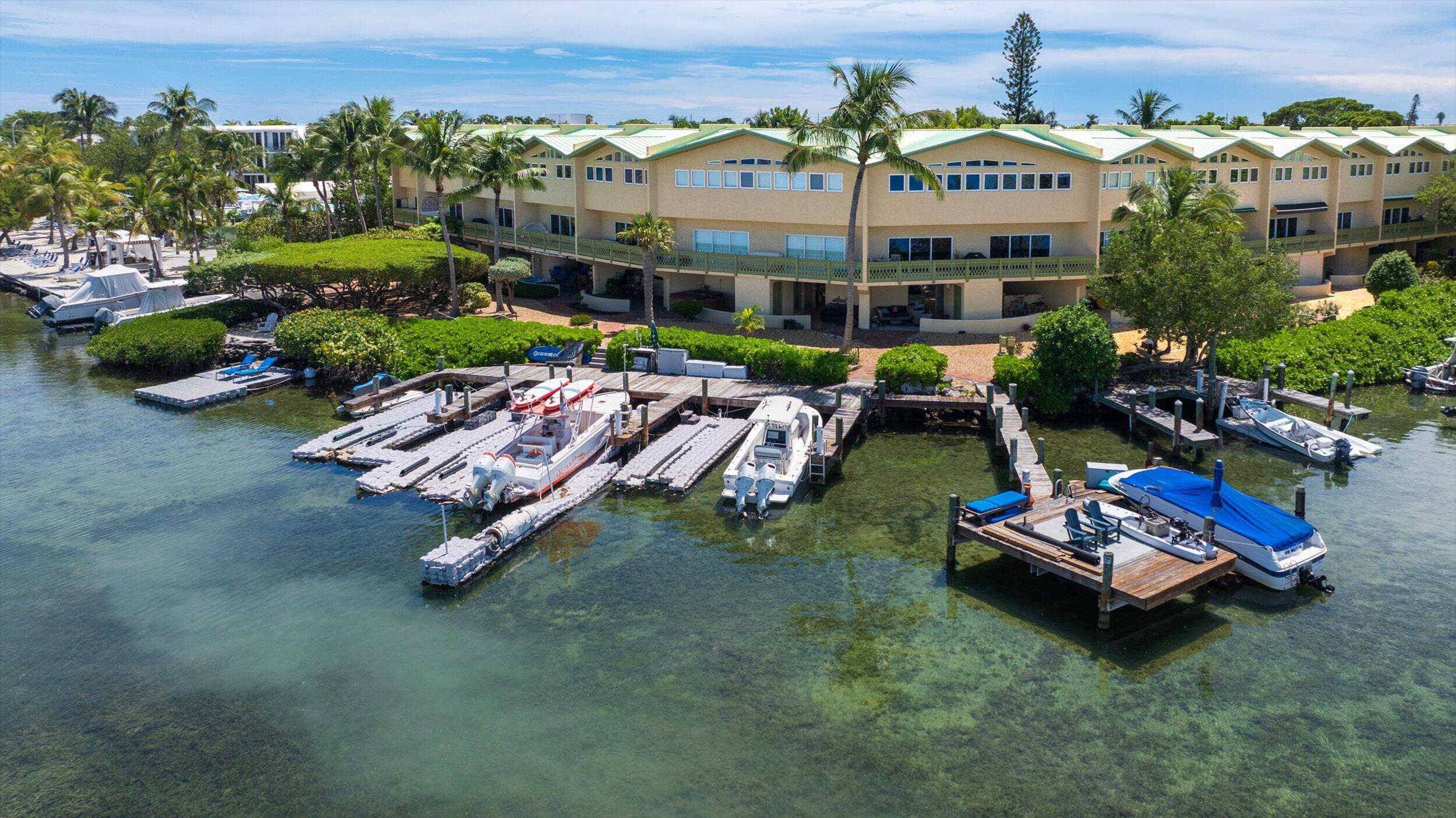 Waterfront condominium buildings with private docks and boats along clear shallow water.