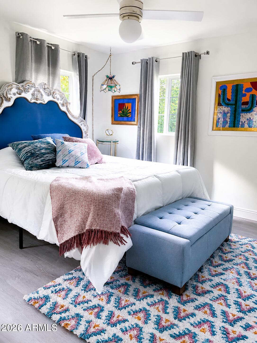 Furnished bedroom with an ornate blue headboard, colorful Southwestern artwork, and a blue bench.