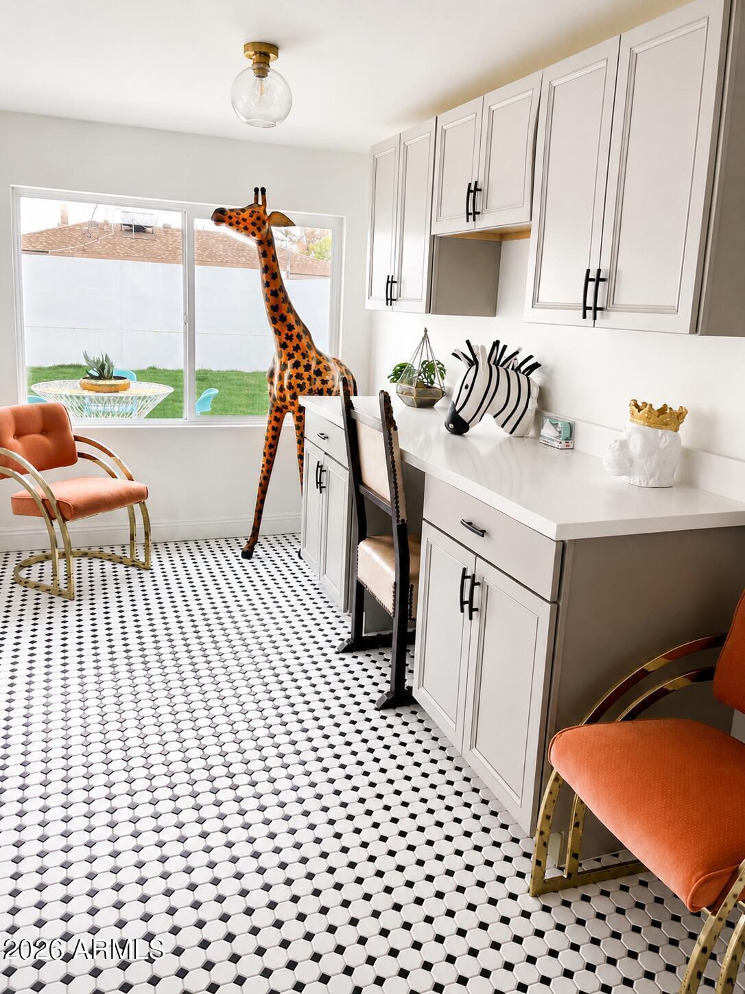 Bright kitchen with geometric tile flooring, orange chairs, and giraffe and zebra decorations.