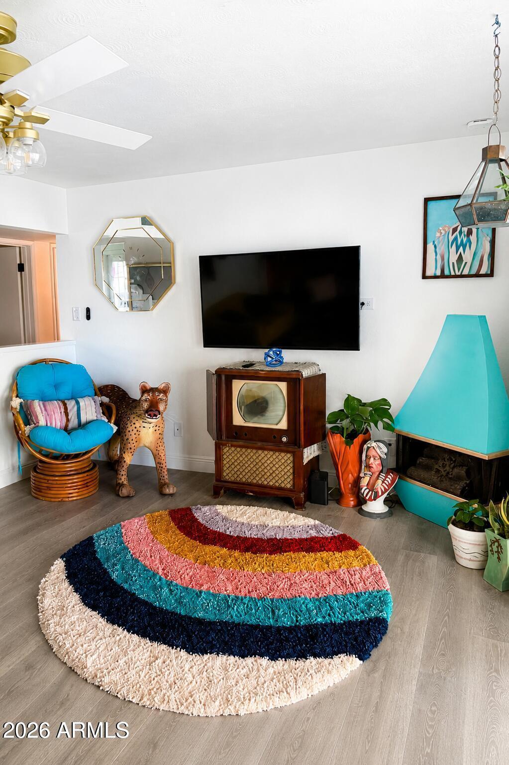 Living room with a colorful circular rug, turquoise fireplace, and vintage television cabinet.