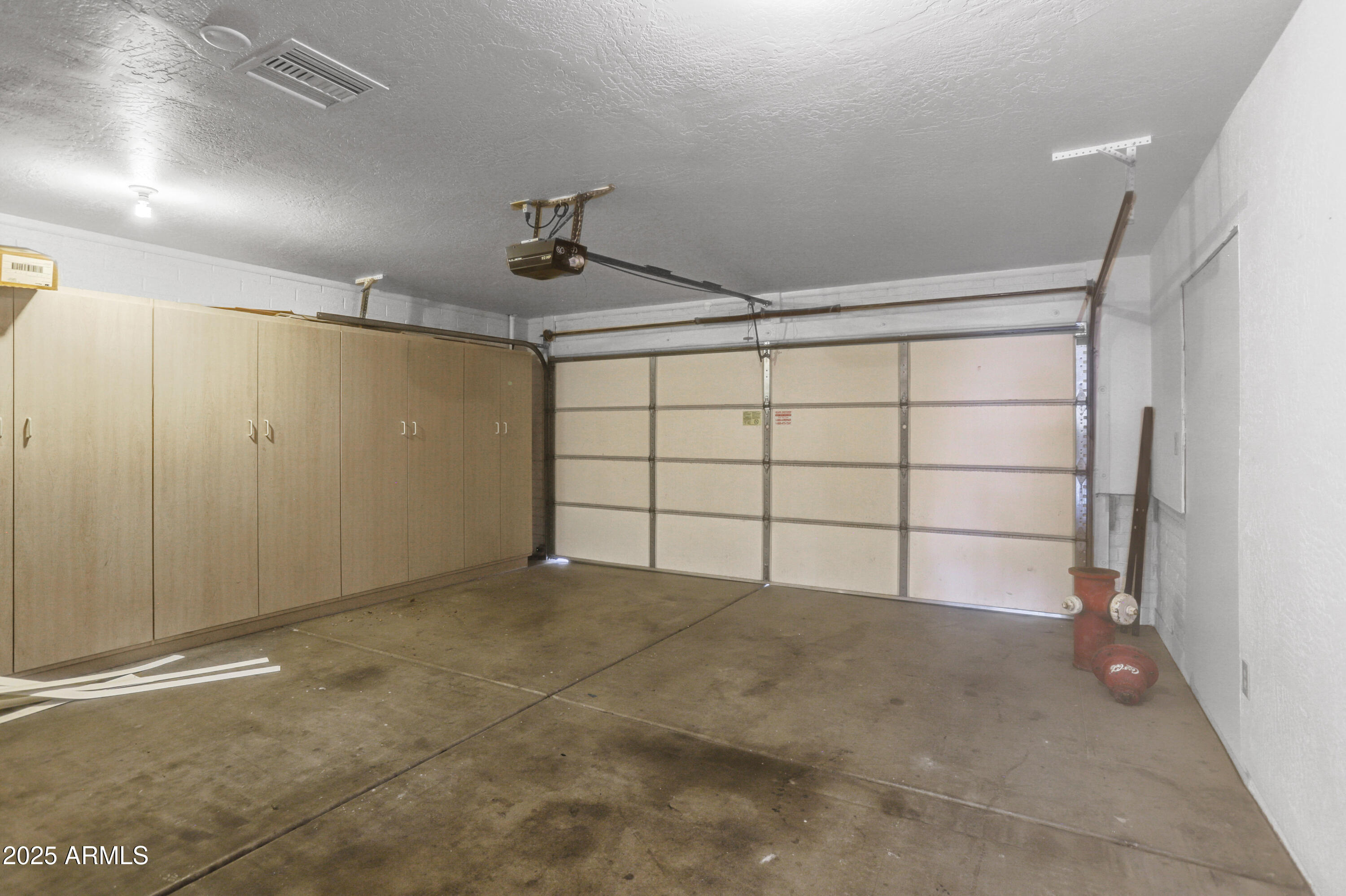 Empty garage with built-in storage cabinets, a closed overhead door, and a concrete floor.