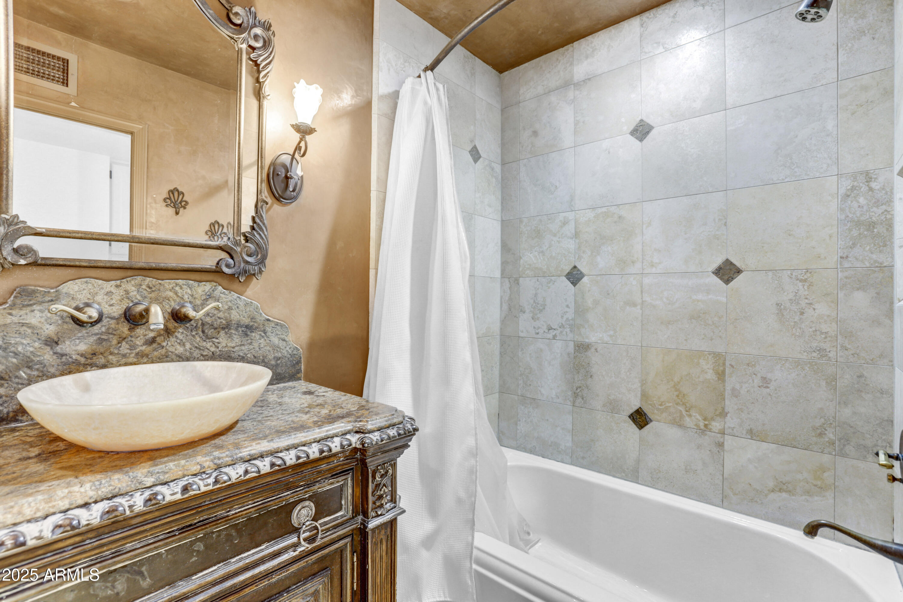Bathroom with a tiled tub and shower beside an ornate wood vanity and vessel sink.