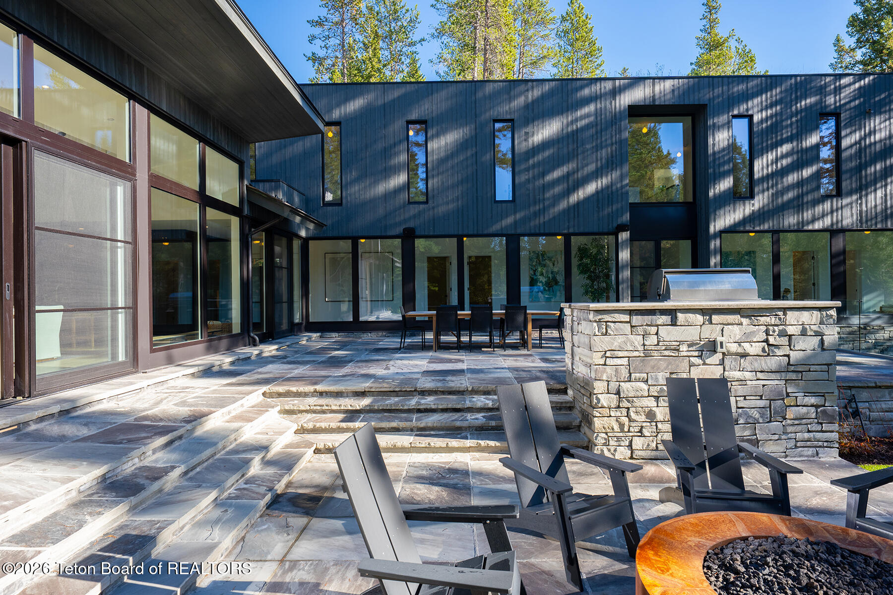 Modern home with a stone patio, outdoor seating, barbecue island, and fire pit