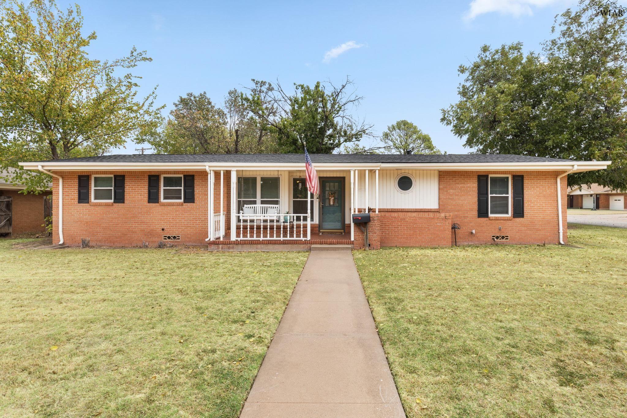Red brick ranch house with a covered porch, circular window, and American flag.