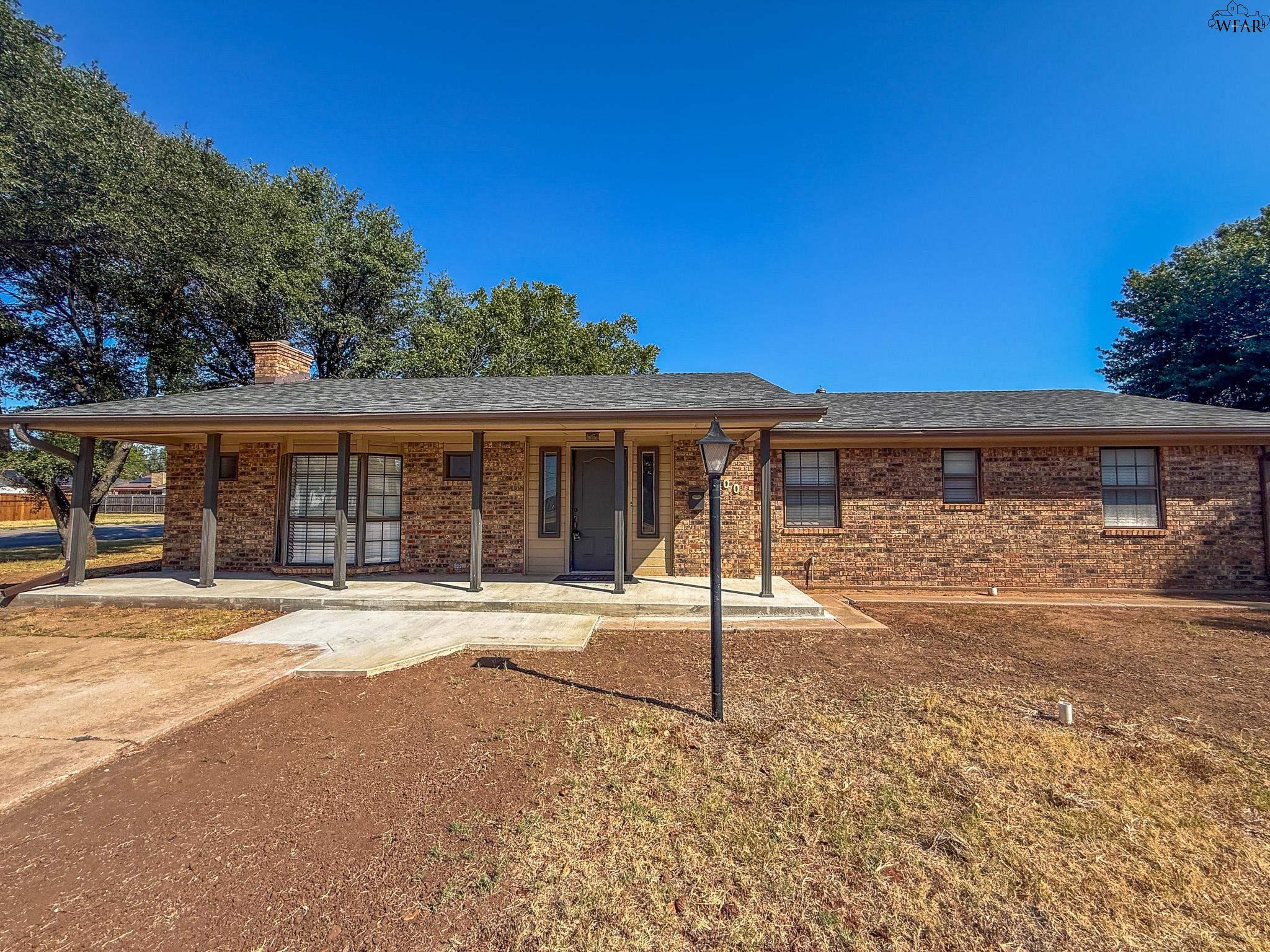 Single-story brick house with a long covered porch and concrete walkway.
