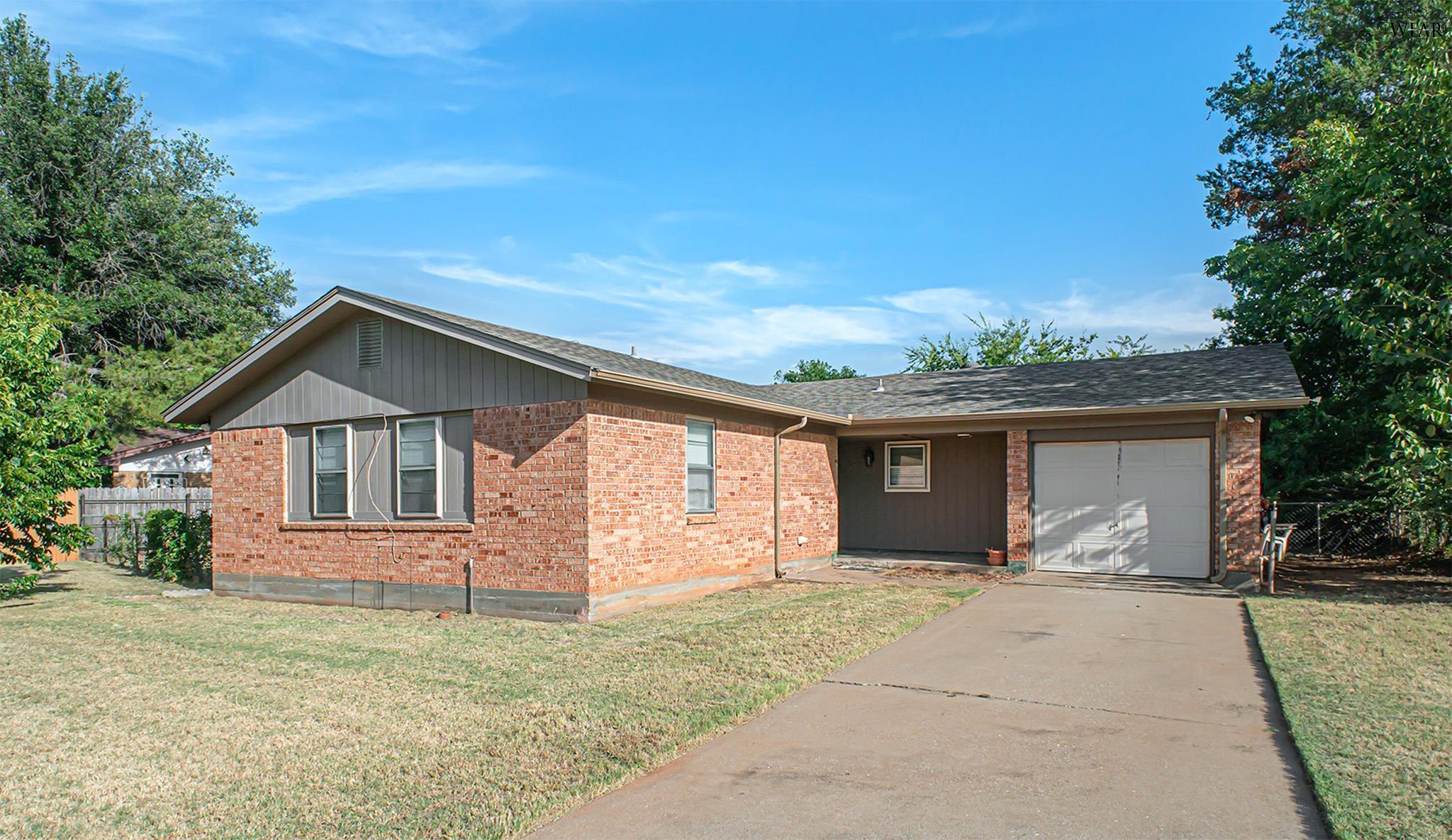 Brick ranch house with gray siding, attached garage, and a wide concrete driveway.