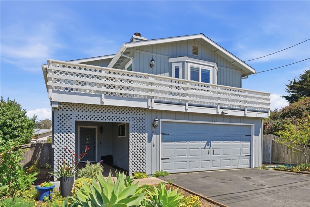 Blue two-story house with a broad white balcony, lattice panels, and an attached garage.