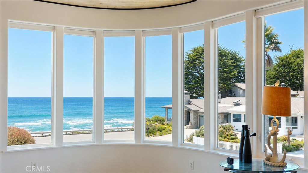 Room with curved ocean-view windows and binoculars on a glass table